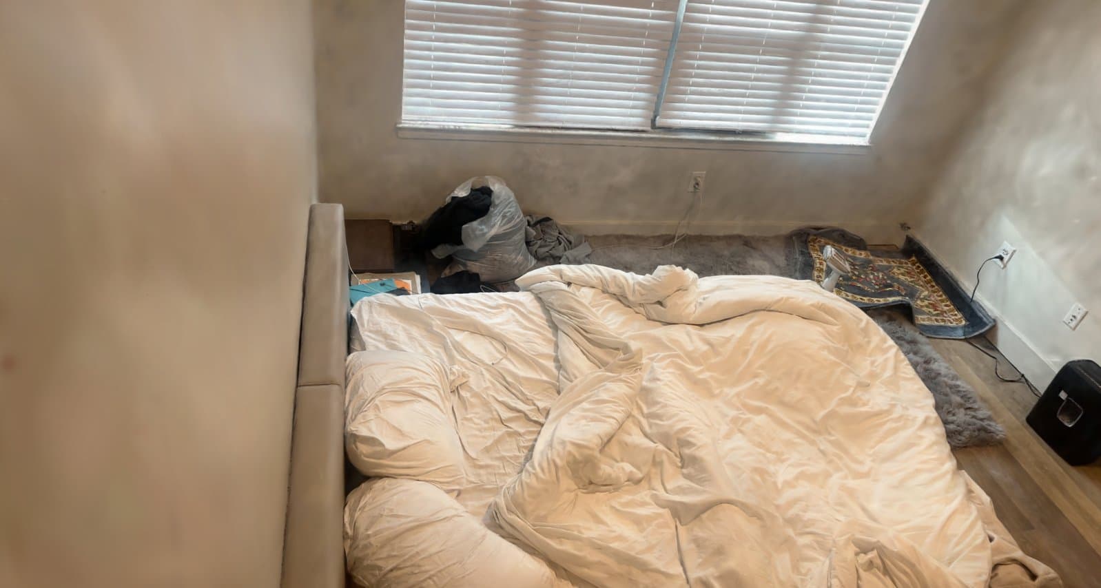 Photorealistic Spatia reconstruction of a bedroom: unmade bed, window blinds, rug and floorboards rendered from the trained Gaussian-splat model
